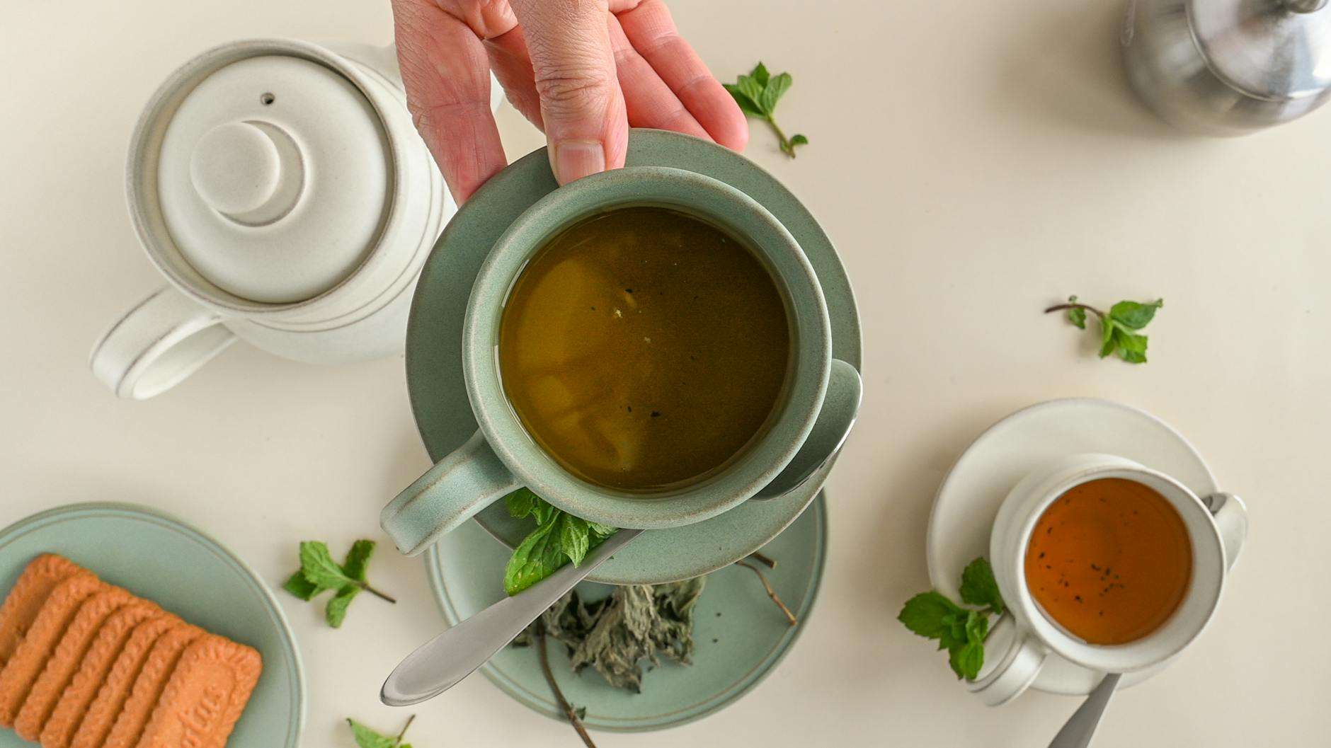 a hand holding a saucer with cup of coffee